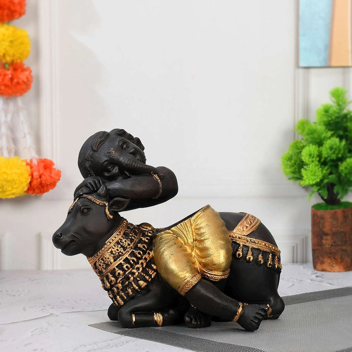 Baby Ganesha Resting on Cow – Elegant Black & Gold Decorative Showpiece